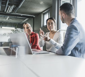 Businesswoman explaining colleagues through gestures in meeting at office