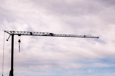 Low angle view of crane at construction site against sky