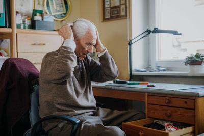 Full length of man sitting on table at home