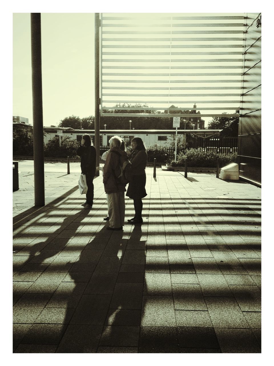 transfer print, walking, auto post production filter, men, architecture, shadow, full length, person, city, lifestyles, built structure, street, rear view, sunlight, city life, building exterior, railing, day