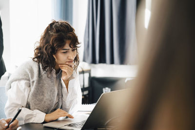 Businesswoman using laptop while sitting in board room