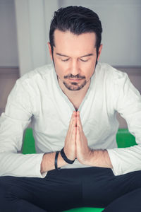 Mid adult man praying while sitting at home