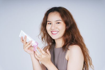 Portrait of young woman smiling against white background