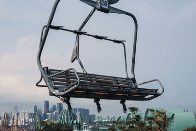 Low angle view of crane in city against sky