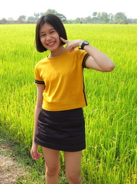 Full length of smiling girl standing on field