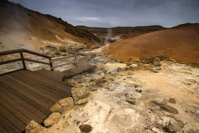 Boardwalk leading towards hot spring against sky