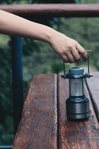 Cropped hand holding lantern on wooden table