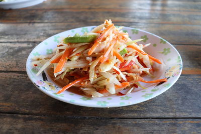 Papaya salad in a dish on the wooden table