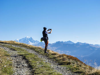 Senior man photographing through smart phone on sunny day at vanoise national park, france