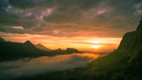 Scenic view of silhouette mountains against sky during sunrise from munnar, kerala