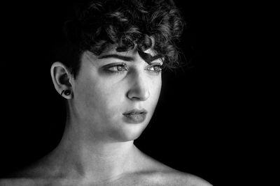 Close-up portrait of young woman against black background