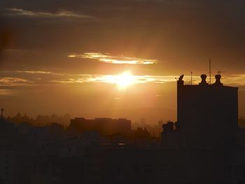 Silhouette buildings against sky during sunset