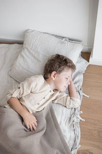 Boy in linen clothes sleeps in natural linen covered bed daytime.