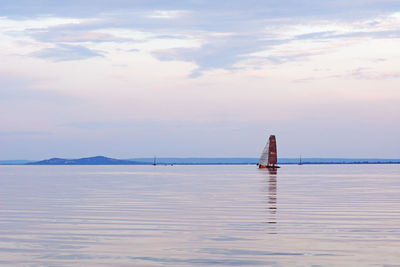 Sailboat in sea against sky during sunset