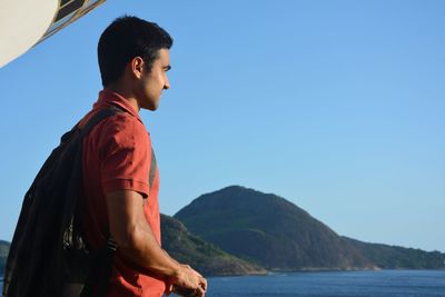 Side view of man standing against clear blue sky