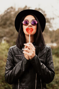 Woman wearing sunglasses holding heart shaped candy