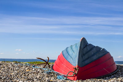 Rowboat moored at beach against sky