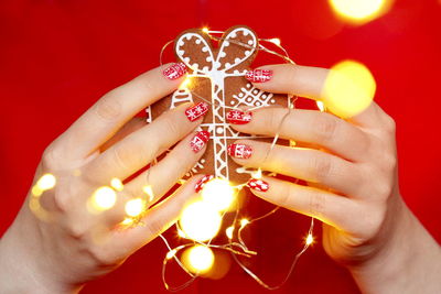 Midsection of woman holding illuminated string light with christmas cookie