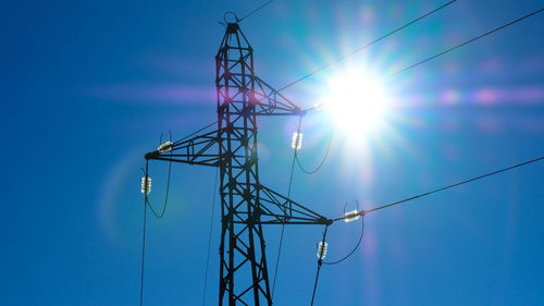 Low angle view of electricity pylon against blue sky