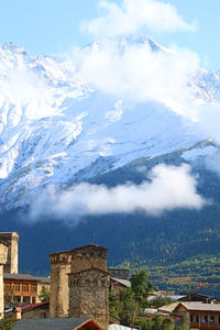 Medieval svan tower with snowcapped caucasus mountains, mestia town, svaneti region, georgia