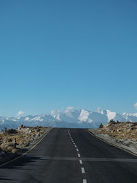 Road by mountains against blue sky