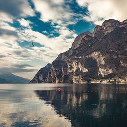 Scenic view of sea by mountain against sky