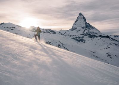 Man standing on snow covered mountain against sky