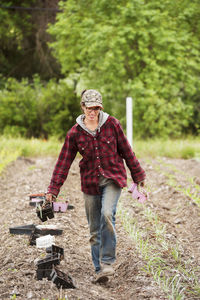 Female farmer carrying seedling trays while walking on farm