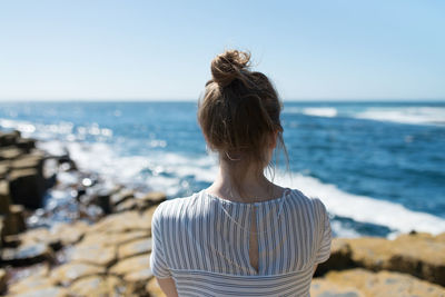 Rear view of woman standing on beach against clear sky