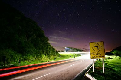 Road sign against sky at night