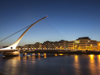 Illuminated george bernard shaw bridge over river liffey in dublin against sky at dusk