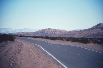 Empty road in desert against clear sky