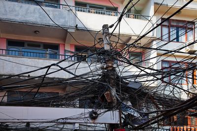Bunch of electrical wires attached to a pole with building in background, kathmandu, nepal