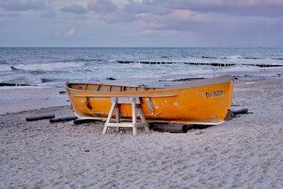 Deck chairs on beach against sky