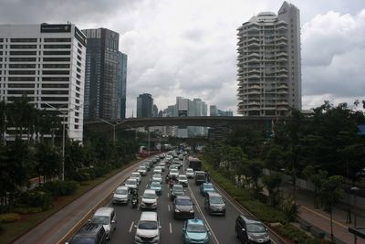 Traffic on road amidst buildings in city against sky