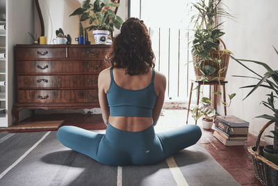 Rear view of woman meditating while sitting at home