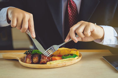 Midsection of businessman having food on table