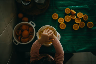 High angle view of hand preparing orange juice on table