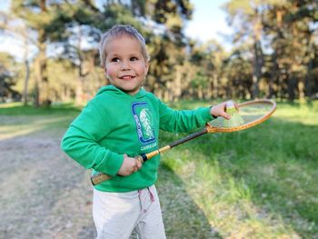 A blond boy toddler  plays  badminton game in the park