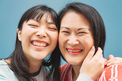 Portrait of smiling mother and daughter against wall
