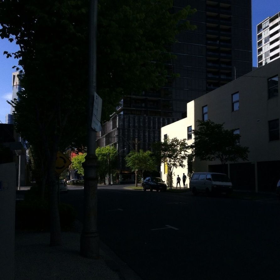 building exterior, architecture, built structure, city, street, car, tree, transportation, land vehicle, road, mode of transport, building, city life, sunlight, city street, residential structure, residential building, shadow, incidental people, outdoors