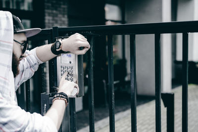 Young man entering password in security system on gate