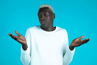 Portrait of young man standing against blue background