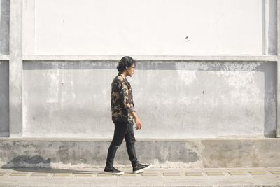 Full length of boy looking through wall