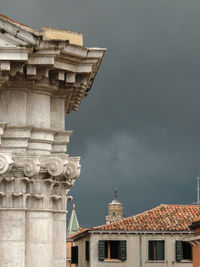 Corinthian column detail of a church with view of campanile di san marco in a stormy day.