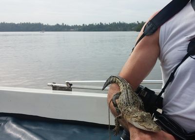 Midsection of photographer with hatchling in boat