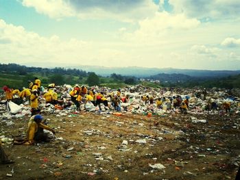 People on mountain against cloudy sky