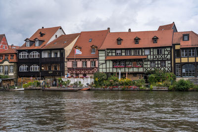 Buildings by river against sky