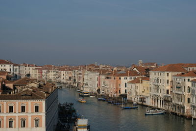 Canal amidst houses in town against clear sky