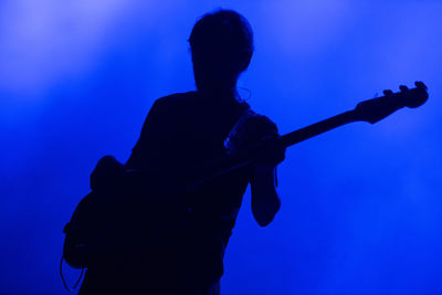 Man playing guitar against blue background